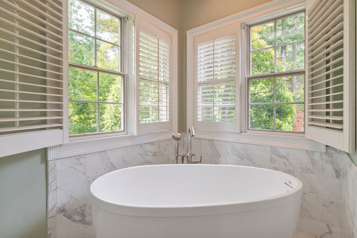 bathroom featuring a ceramic tub and window shutters